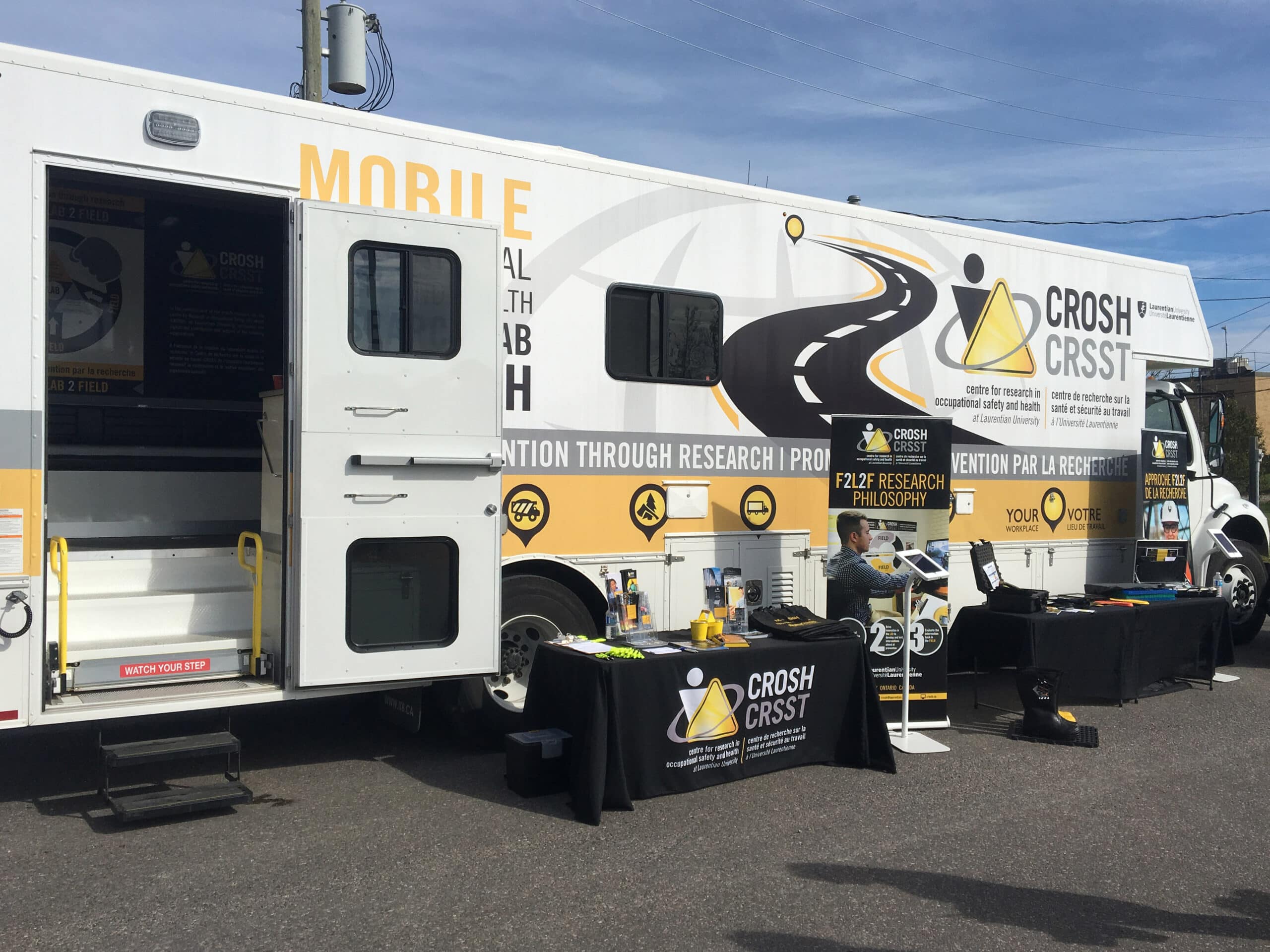 CROSH Mobile Research Lab (M-CROSH) with door open and tables with safety information set-up outside