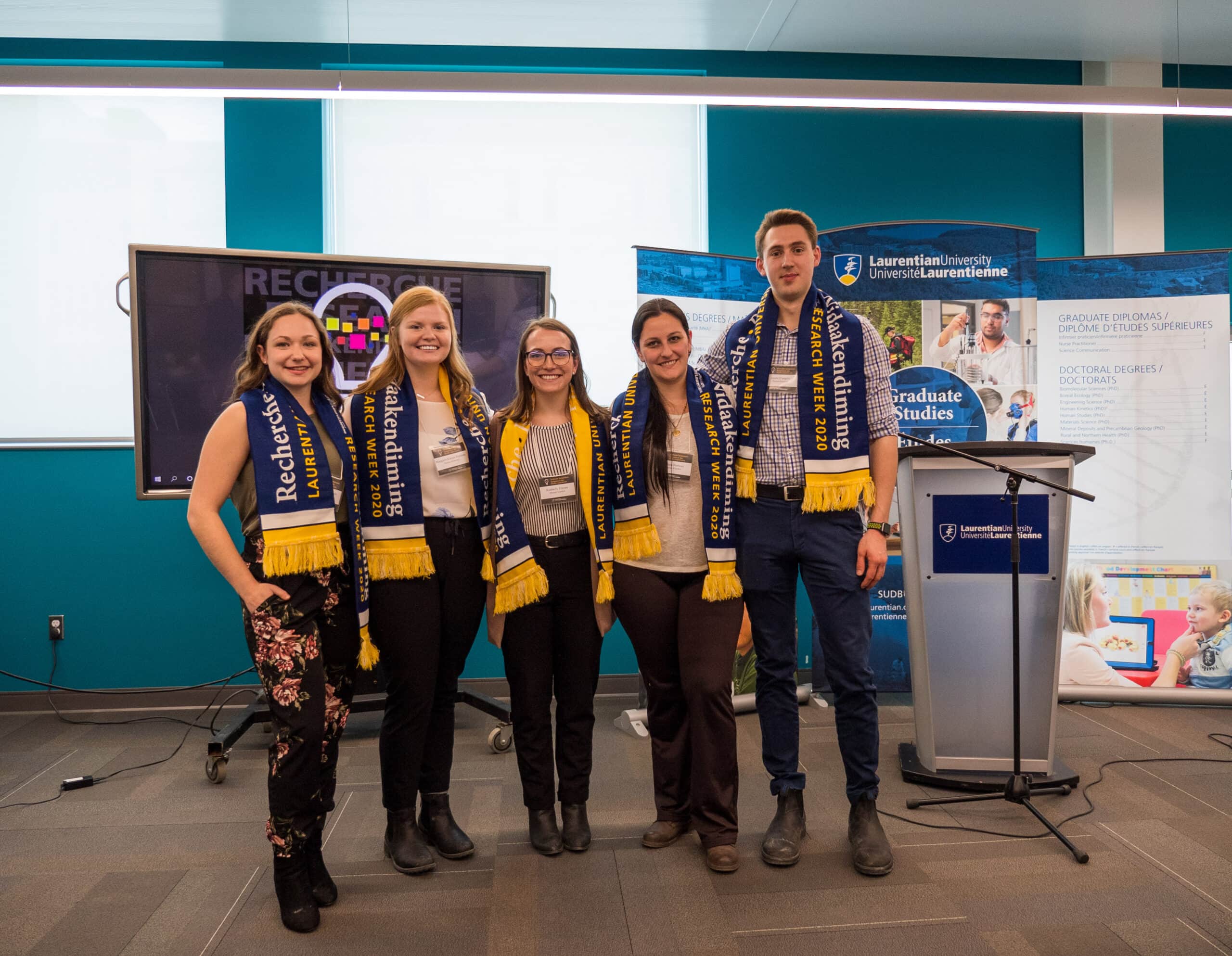 Five students posing beside a podium at Laurentian University's Research Week